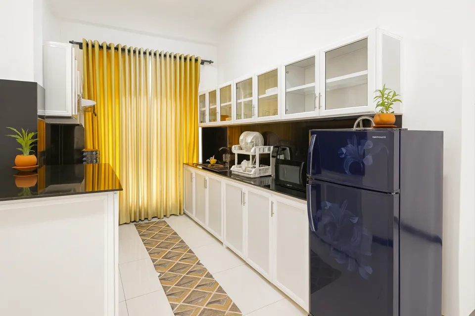Katunayaka apartment kitchen with white cabinets, dark counters and a refrigerator