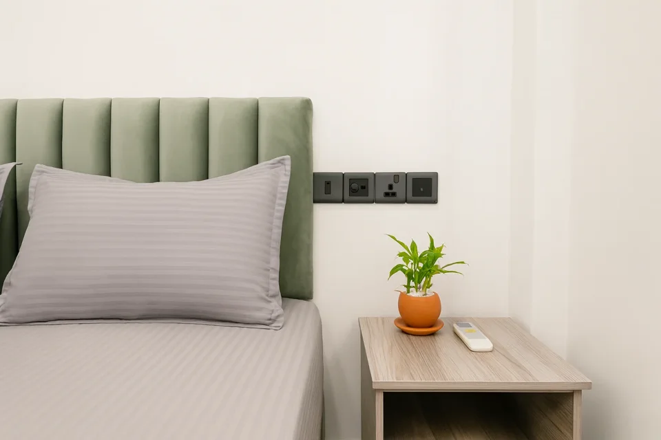 Green upholstered headboard, grey pillow and bedside plant in a first-floor bedroom