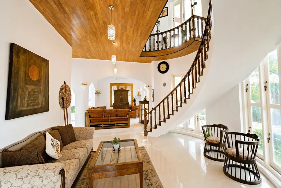 Negombo living area with a sofa, wooden ceiling and curved staircase