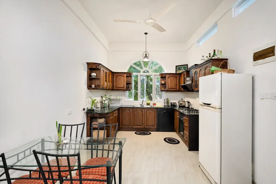 Negombo kitchen with wooden cupboards, refrigerator and tiled floor